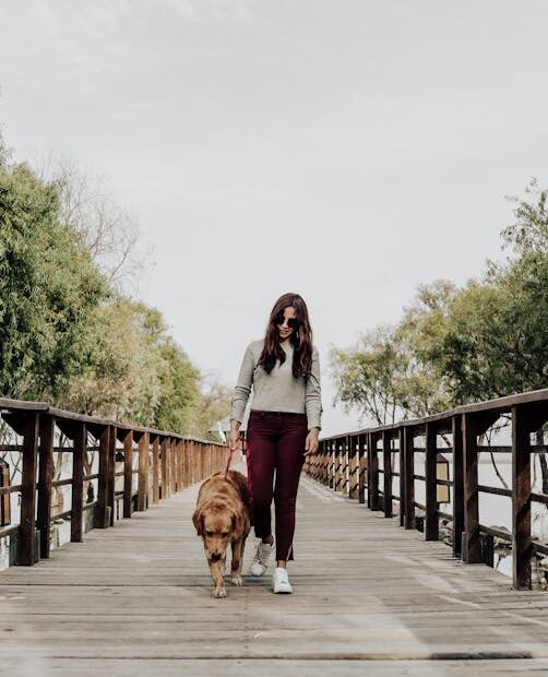 Woman with sunglasses walking dog on a wooden bridge in Jocotepec, Mexico.